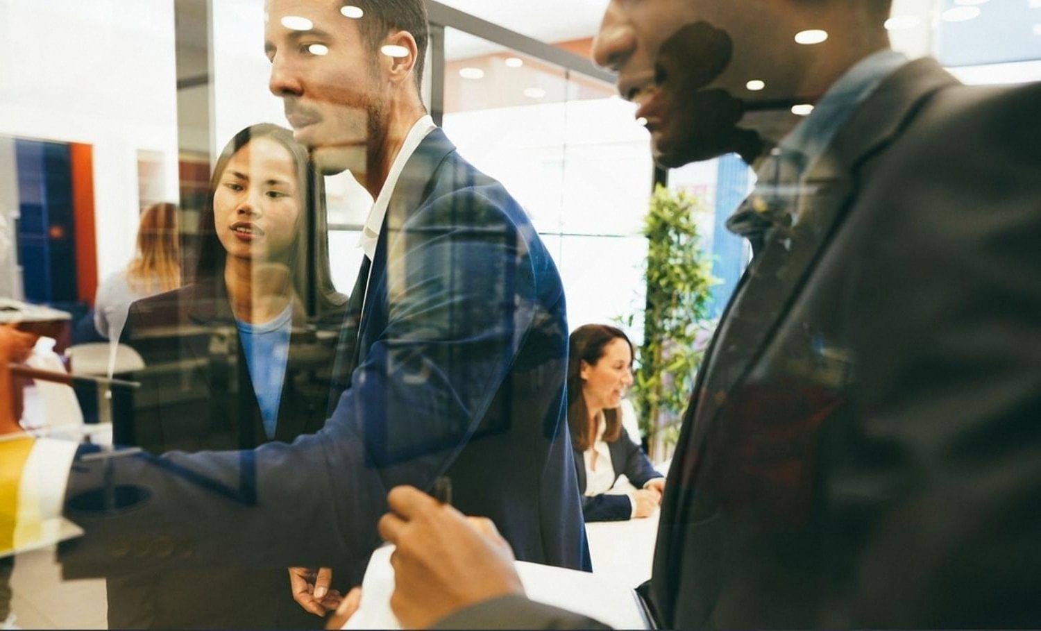 Multinational team reviewing watchlist alerts behind a glass meeting room wall