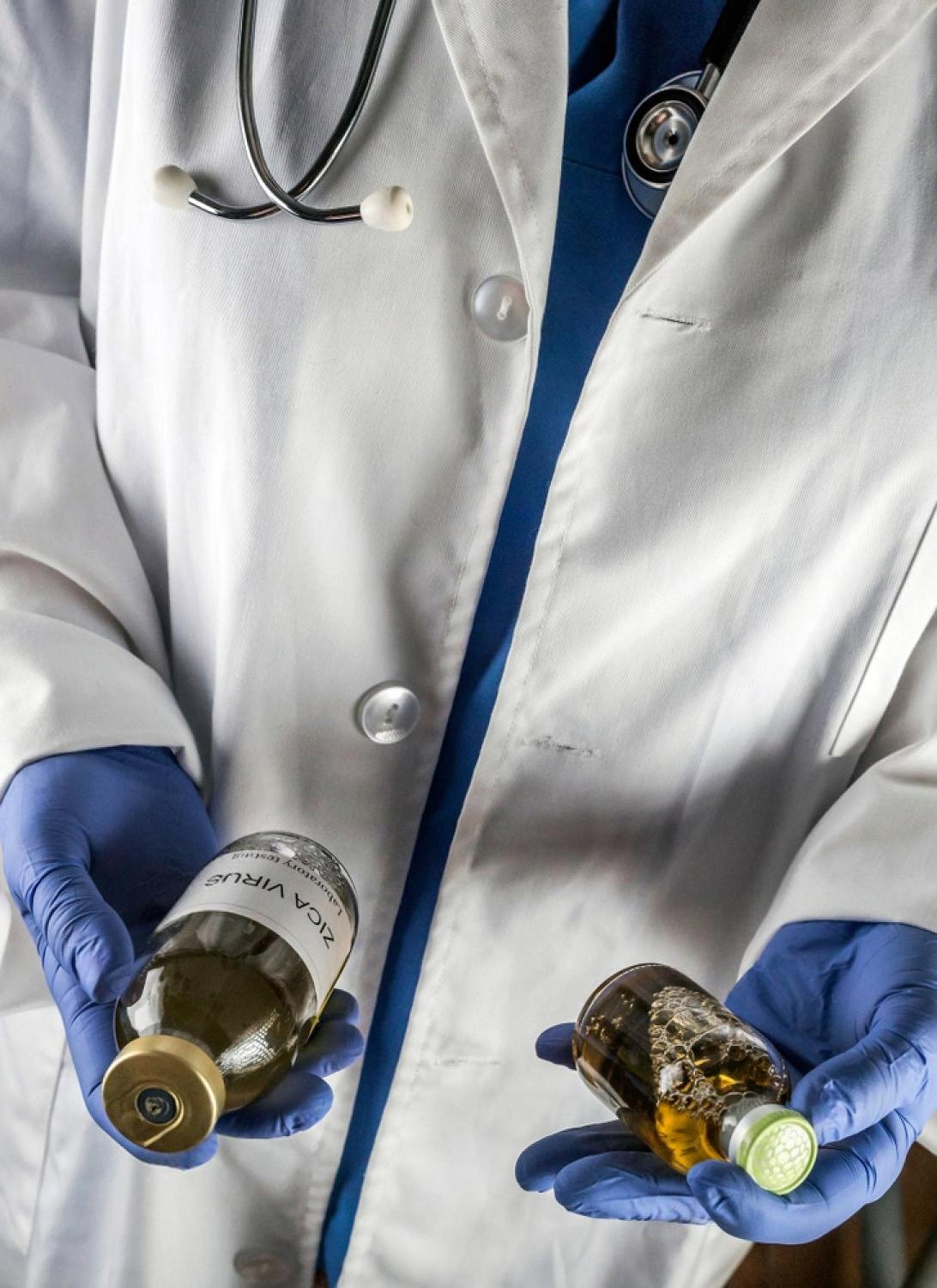 Pest control specialist in gloves holding two bottles of treatment chemicals